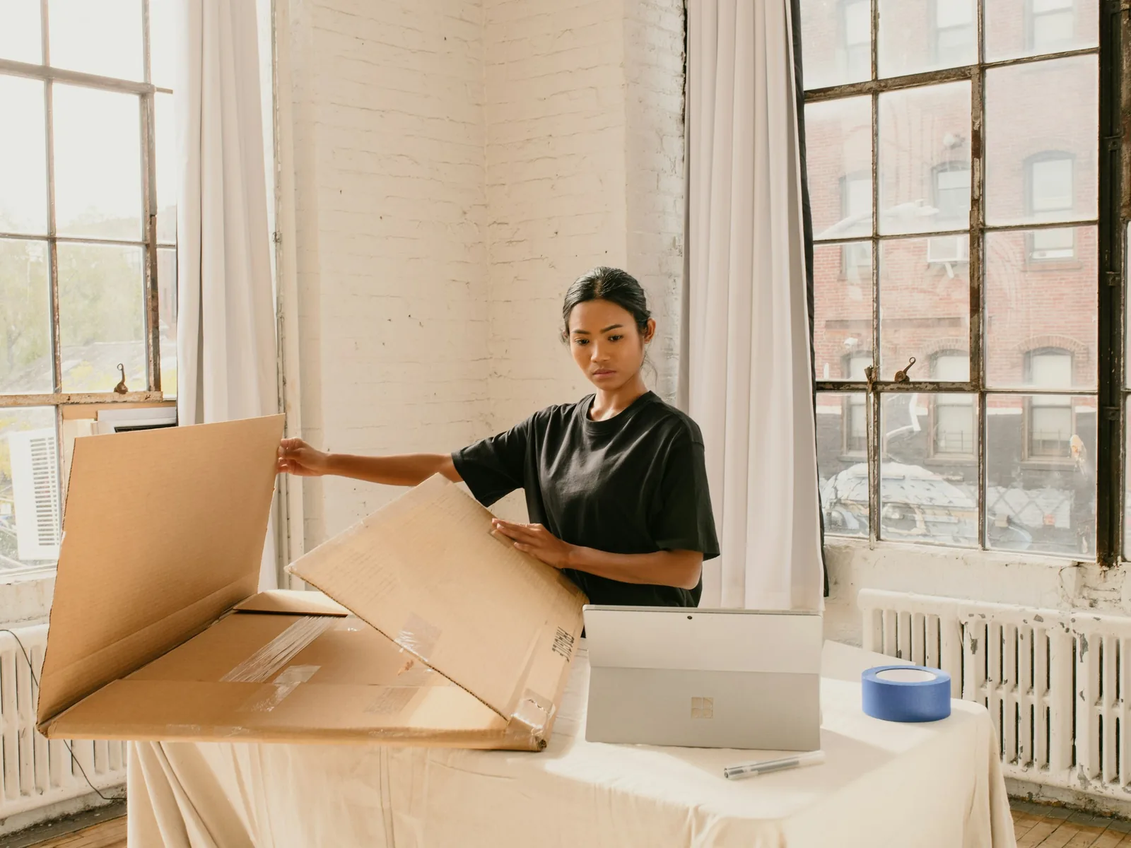 Mulher a montar caixas de envio num loft com luz natural